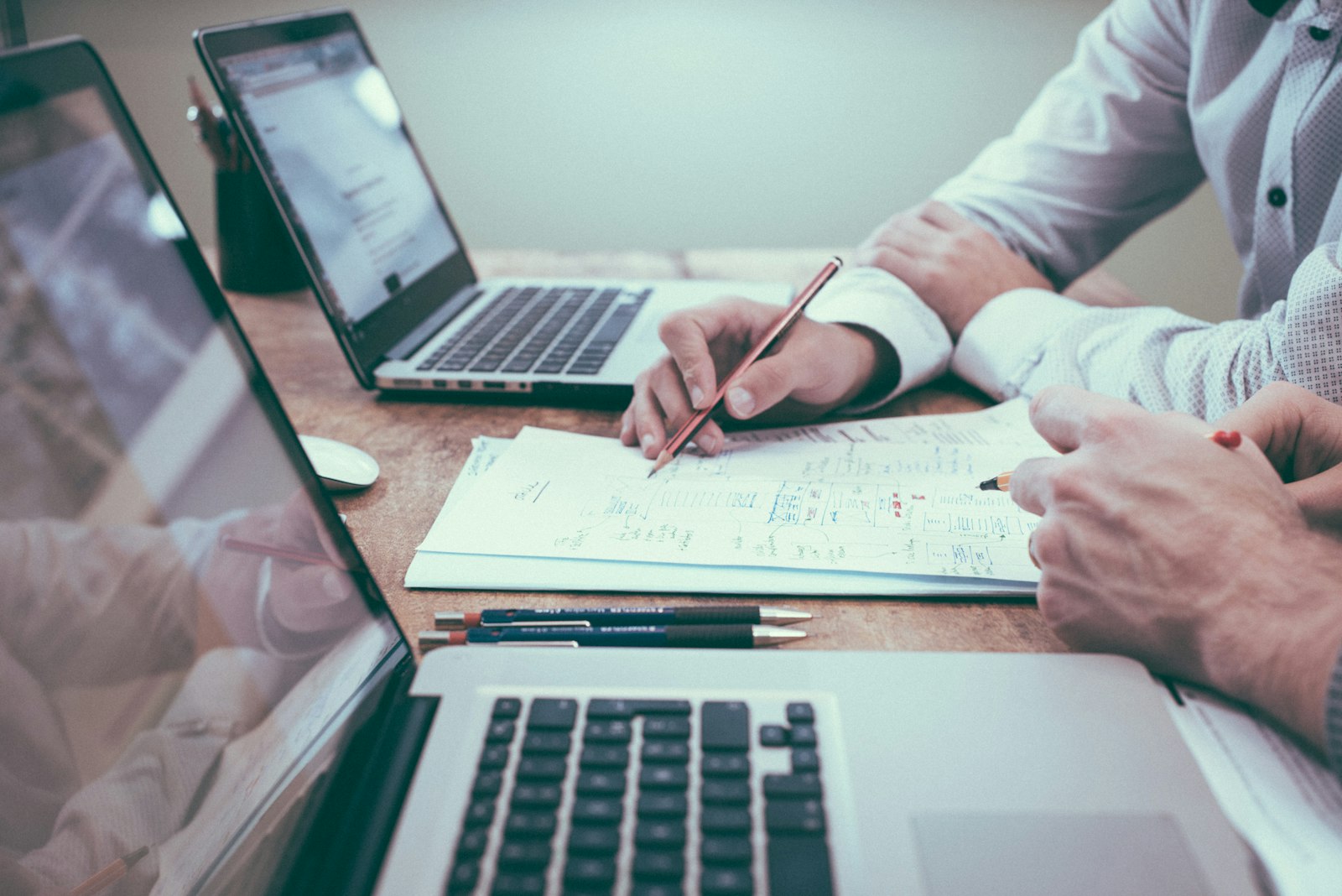 Hands pointing at financial charts and a laptop during a planning meeting